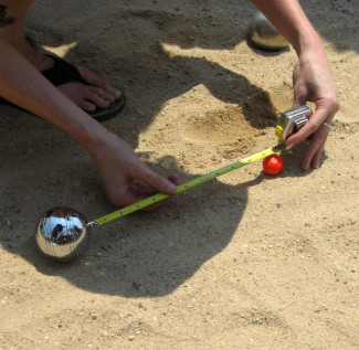 Afbeelding van een persoon die de punten meet aan het einde van een petanque ronde